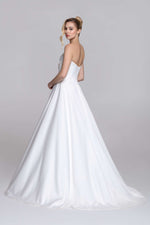 Strapless wedding dress with draped top and slit on the skirt.