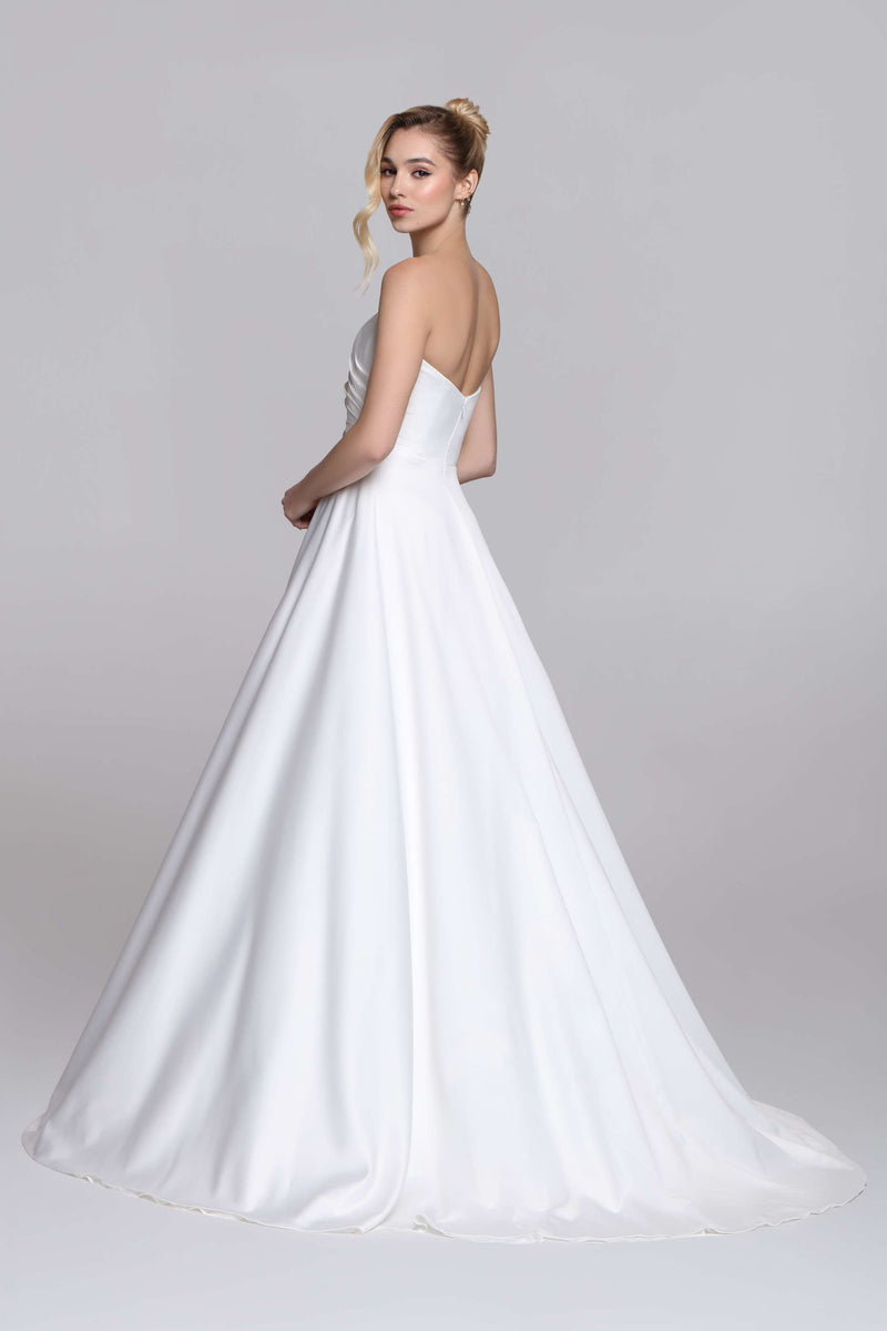 Strapless wedding dress with draped top and slit on the skirt.